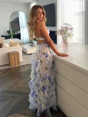 A woman wearing an elegant floral maxi dress with a deep V-neckline and ruffle details, highlighting the backless feature.