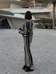 A woman wearing a contrasting striped printed knitted slim midi dress with a round neck and long sleeves.