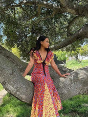 A woman wearing a flowing maxi dress with a lace-up back and ruffled sleeves, perfect for a summer party or holiday event.