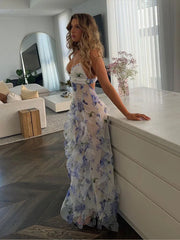 A woman wearing an elegant floral maxi dress with a deep V-neckline and ruffle details, highlighting the backless feature.