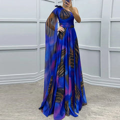 A woman wearing an elegant one-shoulder evening dress with a graphic print and a matching shawl, creating a sophisticated look.