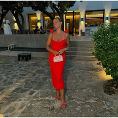 A woman smiling  in a red midi dress, showcasing the off-shoulder neckline and backless style.