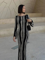 A woman wearing a contrasting striped printed knitted slim midi dress with a round neck and long sleeves.