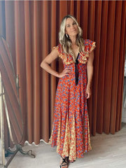 A woman wearing a flowing maxi dress with a lace-up back and ruffled sleeves, perfect for a summer party or holiday event.