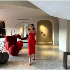 A woman  in a red midi dress, showcasing the off-shoulder neckline and backless style.