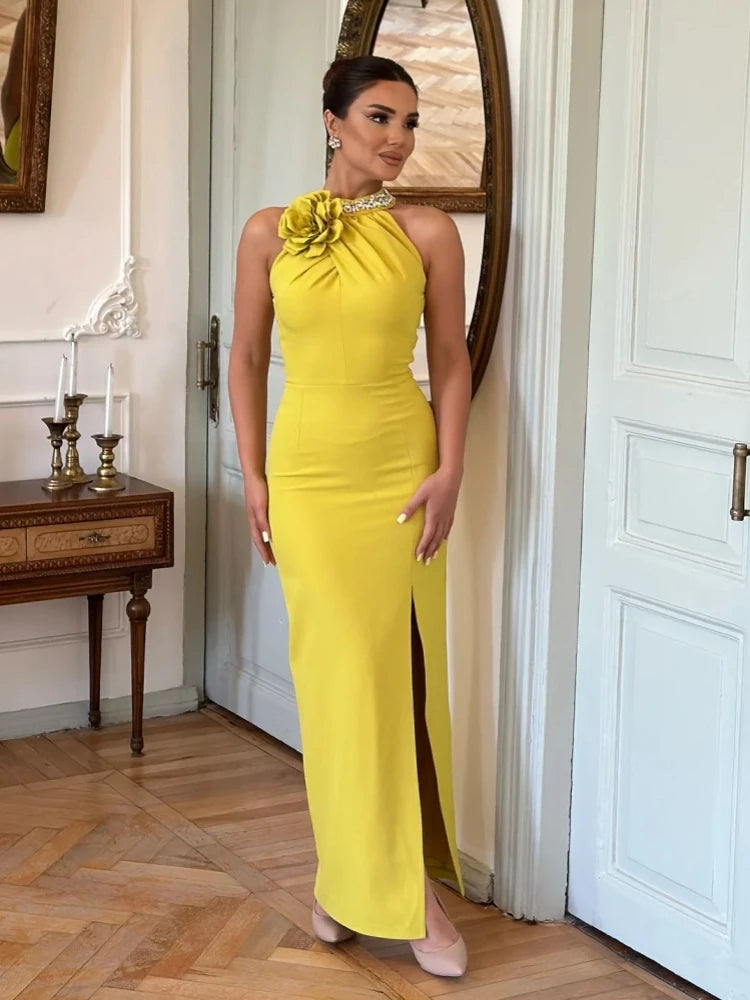 A woman wearing a sparkling yellow maxi dress with a high slit and a sleeveless design, showcasing the intricate crystal details.