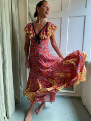 A woman wearing a flowing maxi dress with a lace-up back and ruffled sleeves, perfect for a summer party or holiday event.