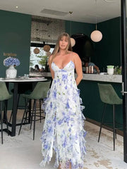 A woman wearing an elegant floral maxi dress with a deep V-neckline and ruffle details, highlighting the backless feature.