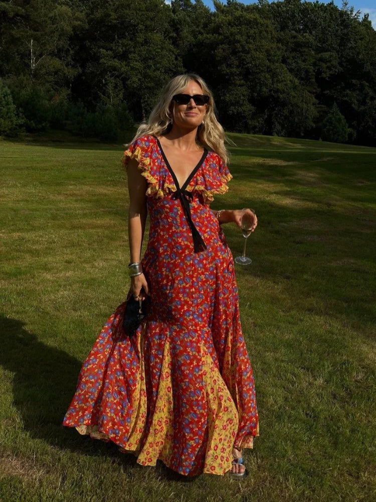 A woman wearing a flowing maxi dress with a lace-up back and ruffled sleeves, perfect for a summer party or holiday event.