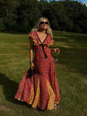 A woman wearing a flowing maxi dress with a lace-up back and ruffled sleeves, perfect for a summer party or holiday event.